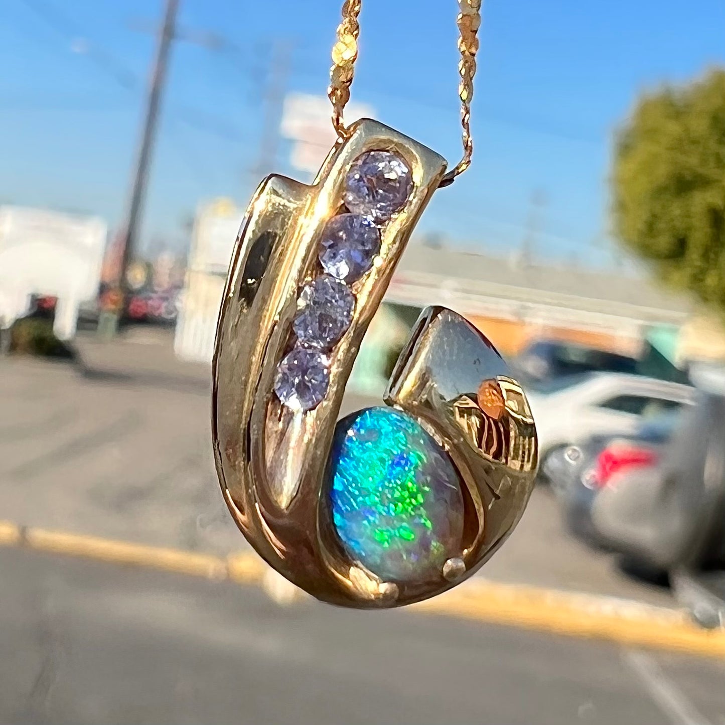 A Lightning Ridge black crystal opal necklace set with blue tanzanite in yellow gold.  Gold chain not included.