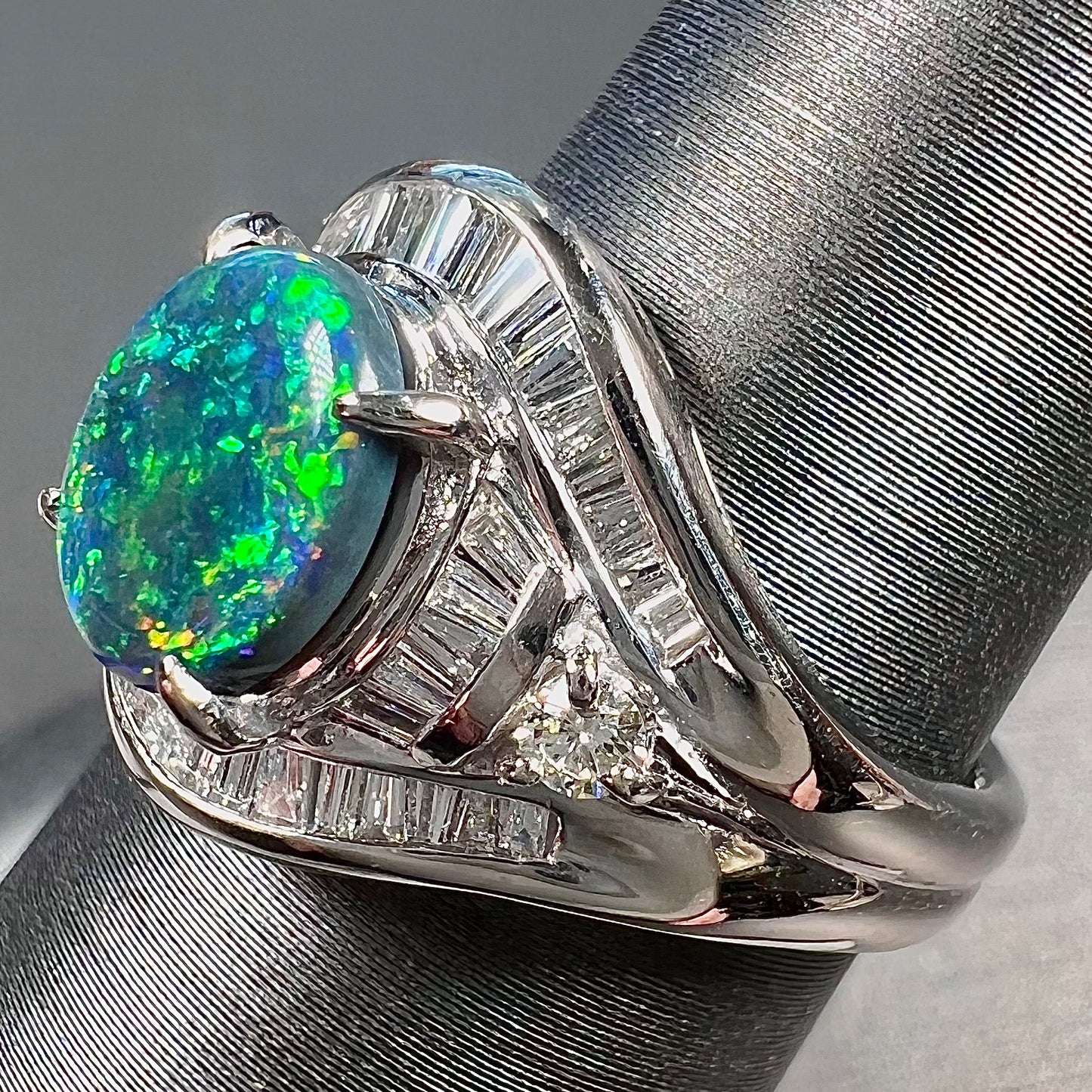A platinum Lightning Ridge black opal ring set with baguette cut diamonds.  The opal is an oval cabochon cut.