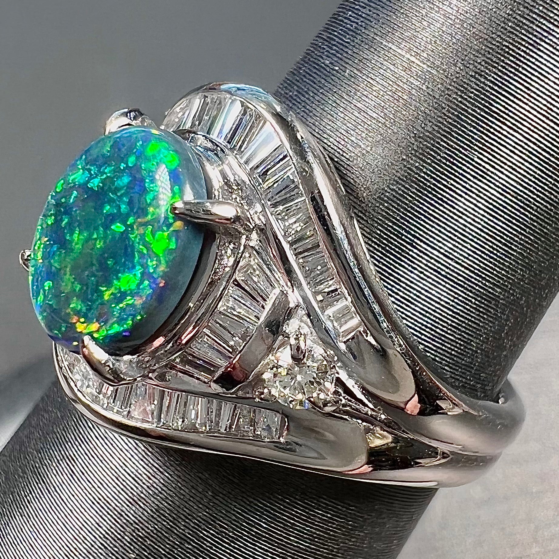 A platinum Lightning Ridge black opal ring set with baguette cut diamonds.  The opal is an oval cabochon cut.