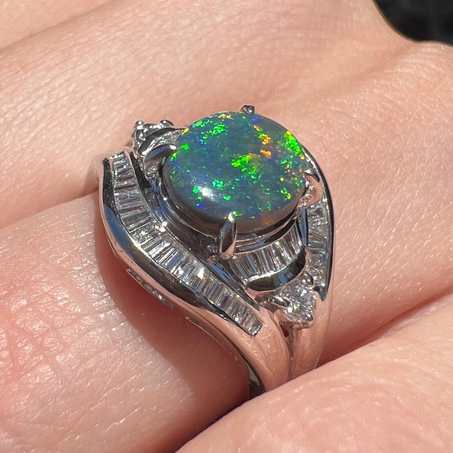 A platinum Lightning Ridge black opal ring set with baguette cut diamonds.  The opal is an oval cabochon cut.