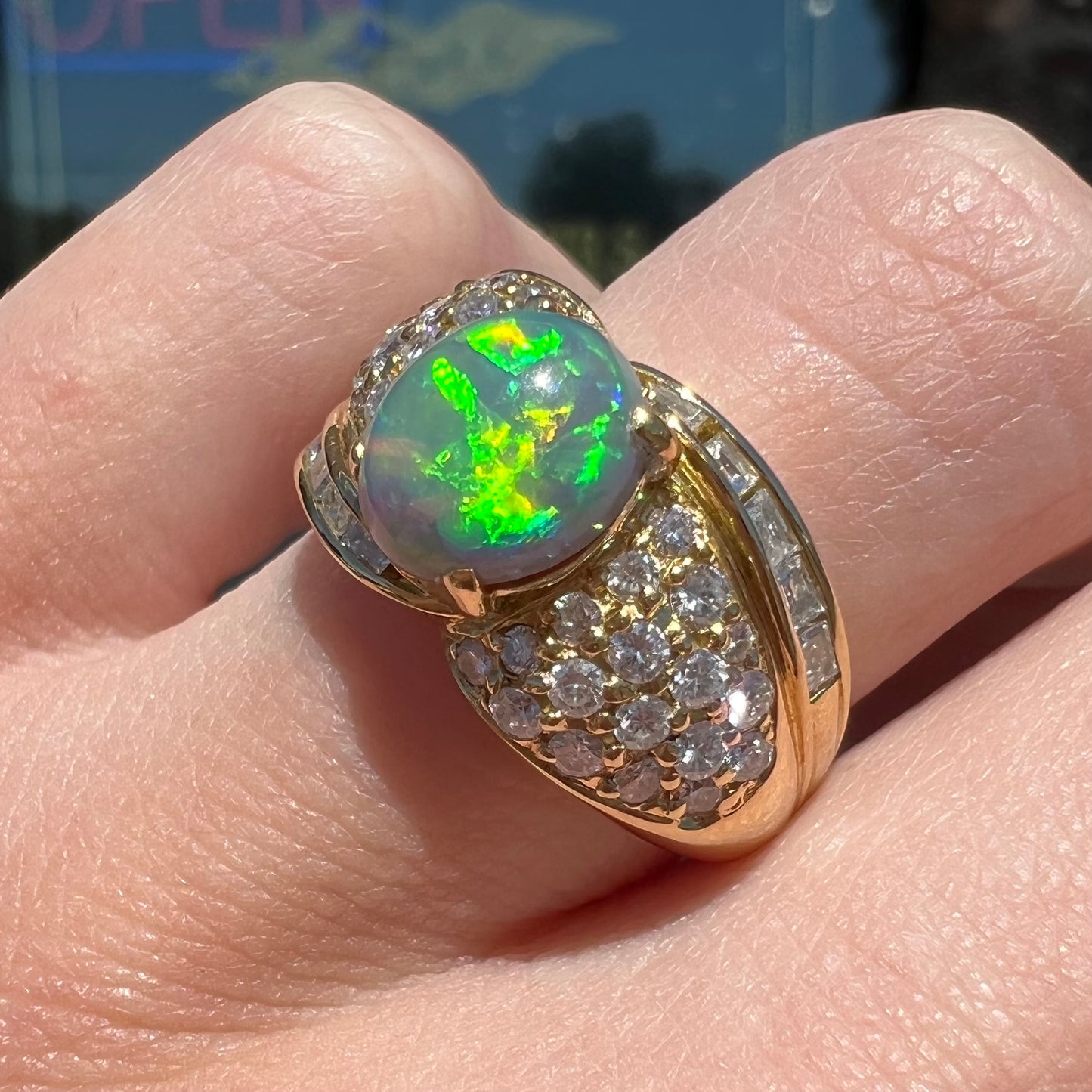 An 18kt yellow gold oval cabochon cut Lightning Ridge black opal ring.  The shank is set with round and baguette cut diamonds.