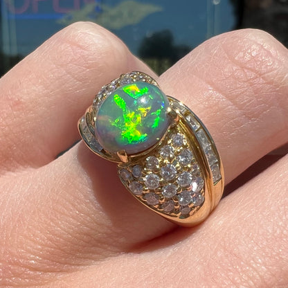 An 18kt yellow gold oval cabochon cut Lightning Ridge black opal ring.  The shank is set with round and baguette cut diamonds.
