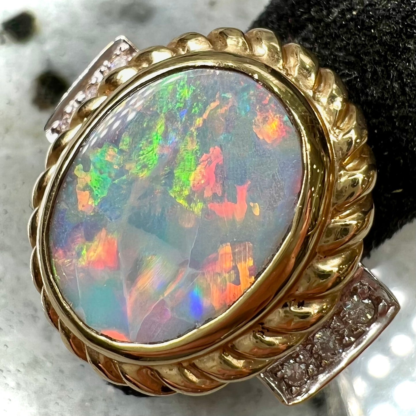 A ladies' Lightning Ridge semi-black opal ring cast in yellow gold and set with diamond accents.