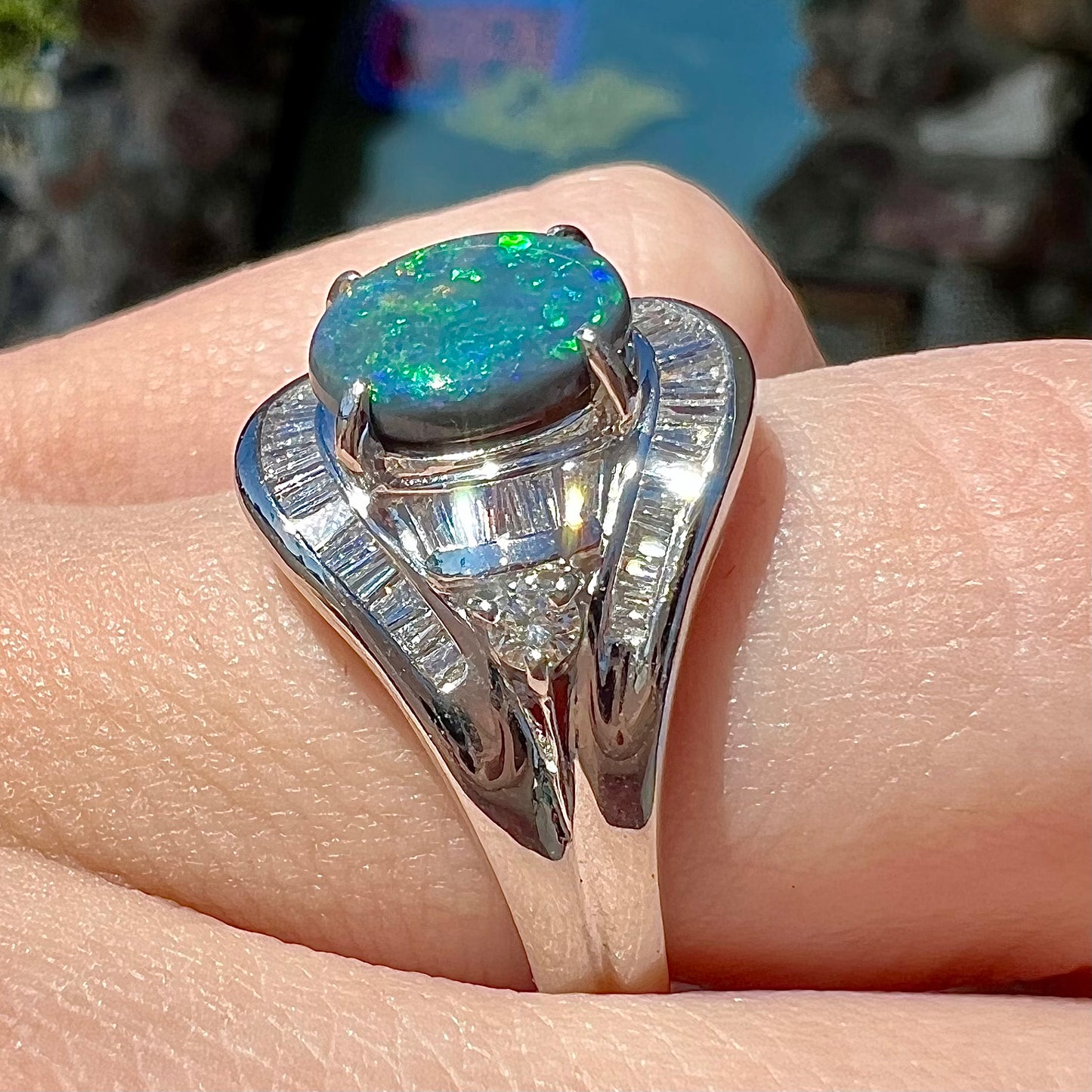 A platinum Lightning Ridge black opal ring set with baguette cut diamonds.  The opal is an oval cabochon cut.
