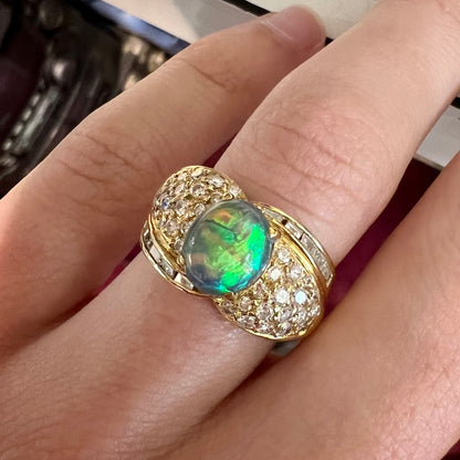 An 18kt yellow gold oval cabochon cut Lightning Ridge black opal ring.  The shank is set with round and baguette cut diamonds.