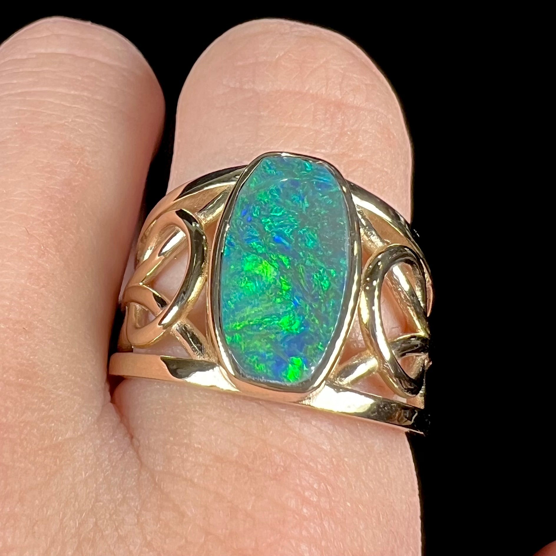 A men's natural Lightning Ridge, Australian black opal solitaire ring cast in yellow gold.