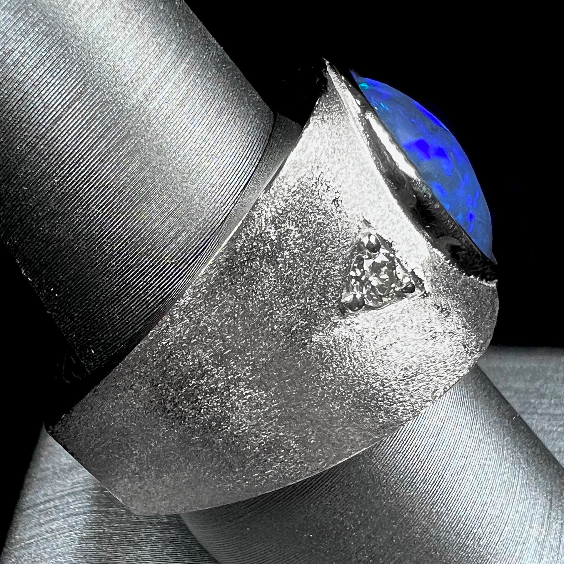 A men's natural black opal and diamond ring cast with a matte finish in white gold.