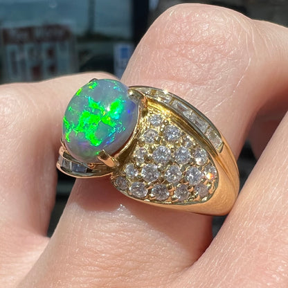 An 18kt yellow gold oval cabochon cut Lightning Ridge black opal ring.  The shank is set with round and baguette cut diamonds.