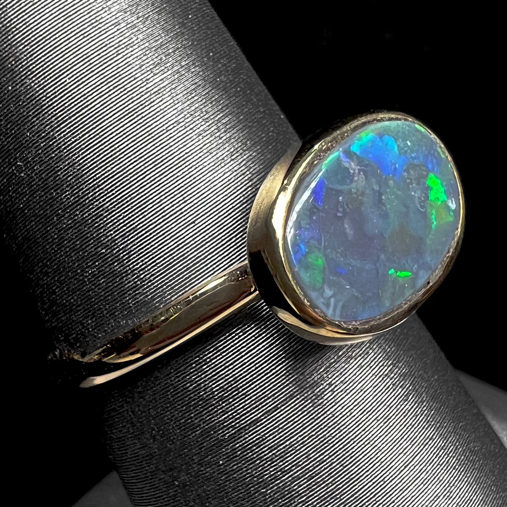 A ladies' yellow gold black opal solitaire ring from Lightning Ridge, Australia.