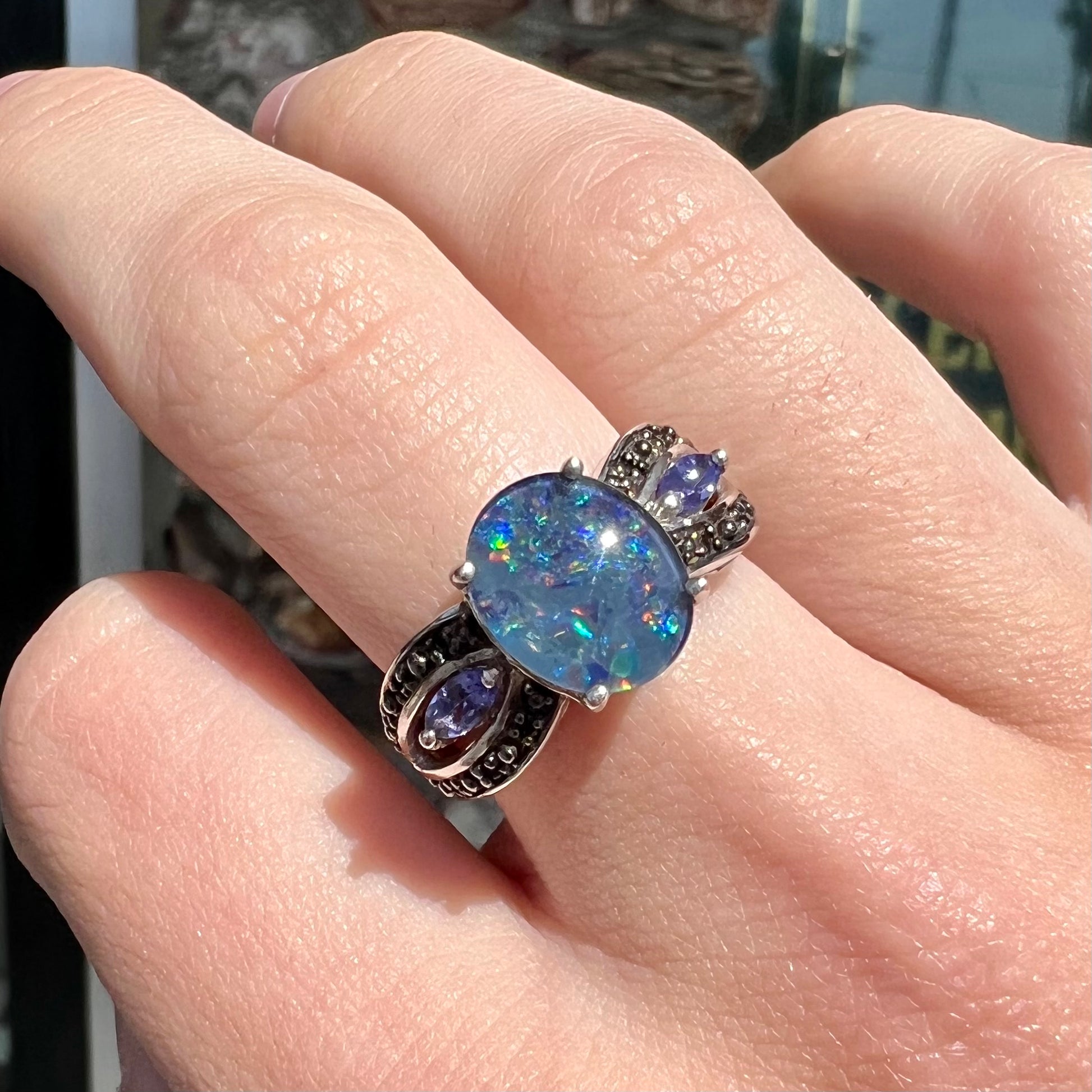 A sterling silver black opal triplet ring set with black spinel and marquise cut tanzanite accent stones.