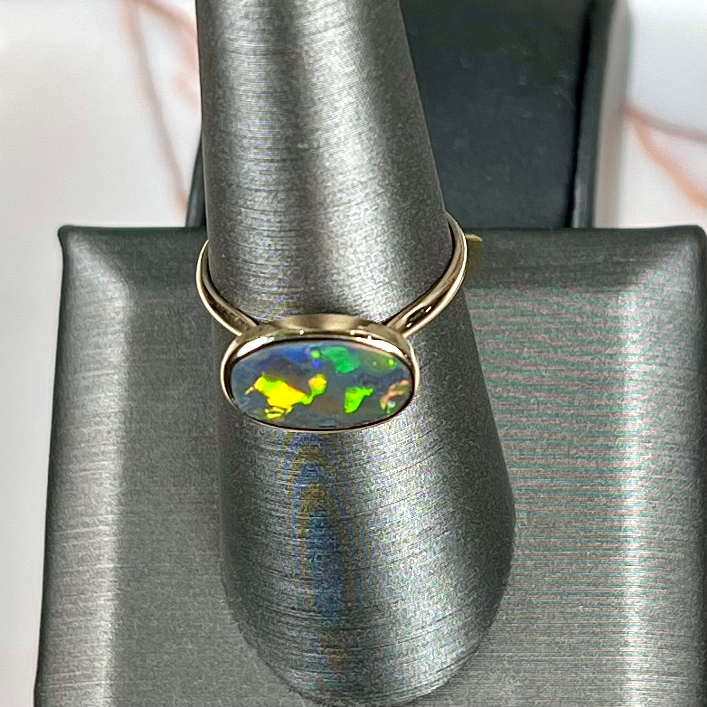 A handmade Lightning Ridge black opal solitaire ring in yellow gold.  Fire is green.