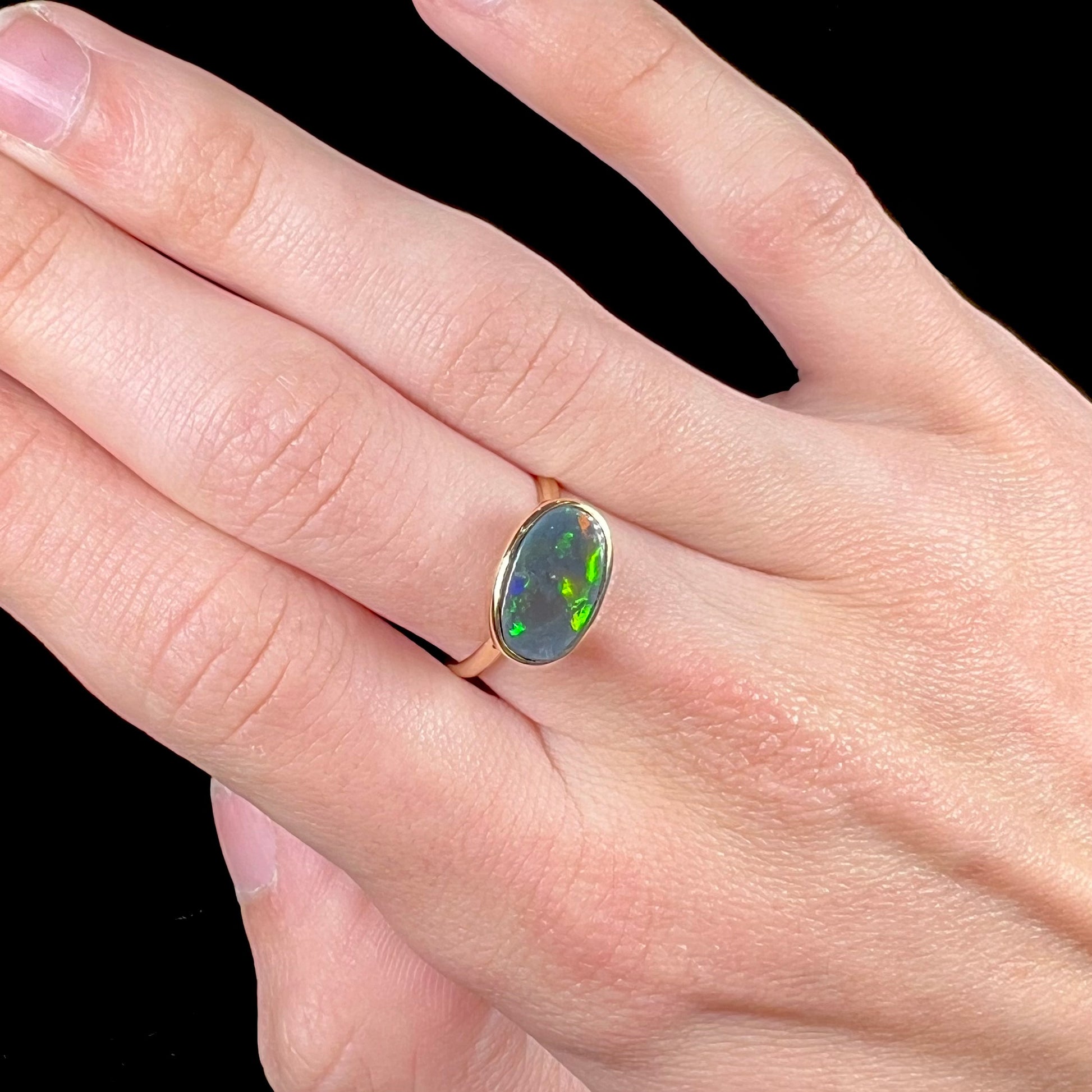 A ladies' yellow gold black opal solitaire ring from Lightning Ridge, Australia.