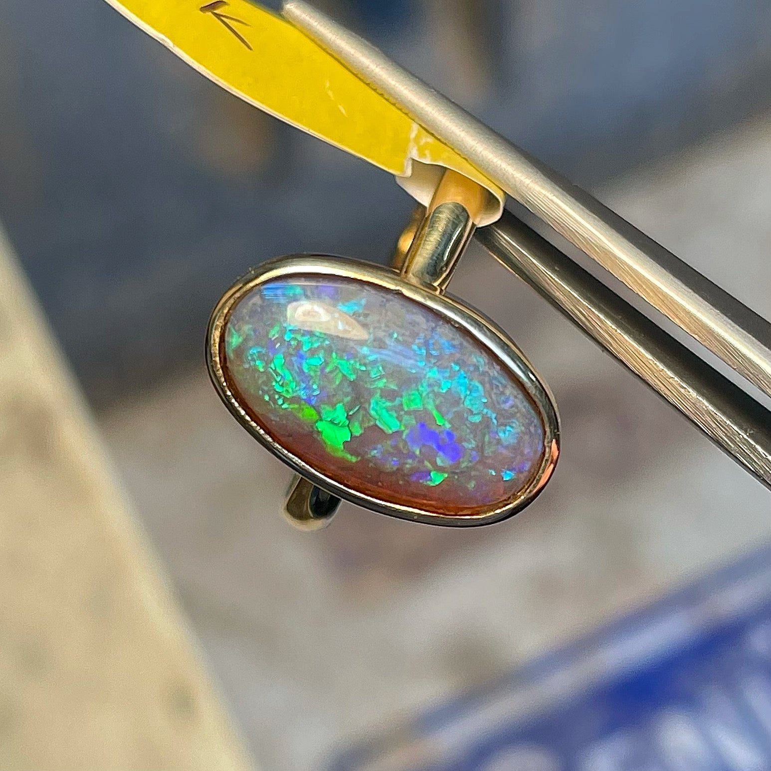 A simple yellow gold solitaire ring with a bezel set Lightning Ridge black crystal opal from Australia.