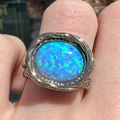 A filigree etched two tone silver and gold spinner ring set with a lab created black opal.