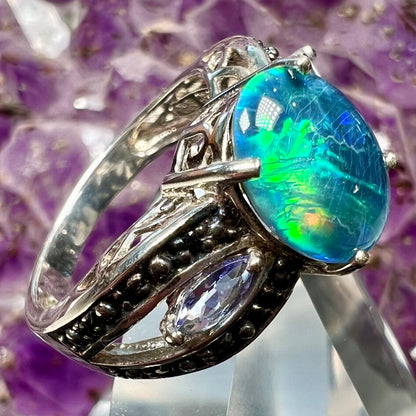 A sterling silver ring set with a black opal triplet, two marquise cut tanzanites, and round black spinel accent stones.