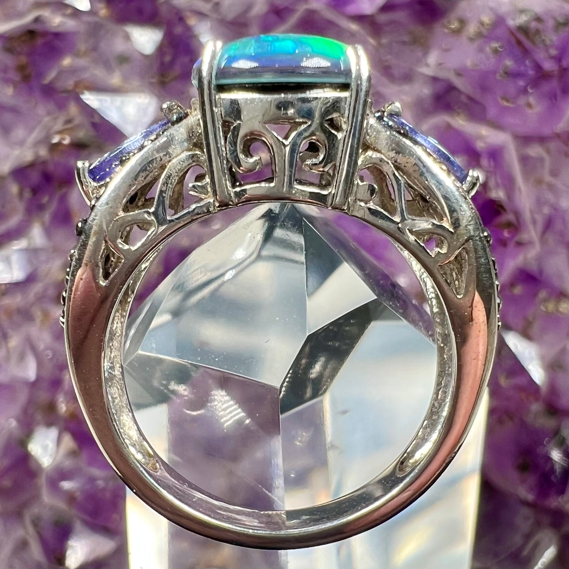 A sterling silver ring set with a black opal triplet, two marquise cut tanzanites, and round black spinel accent stones.