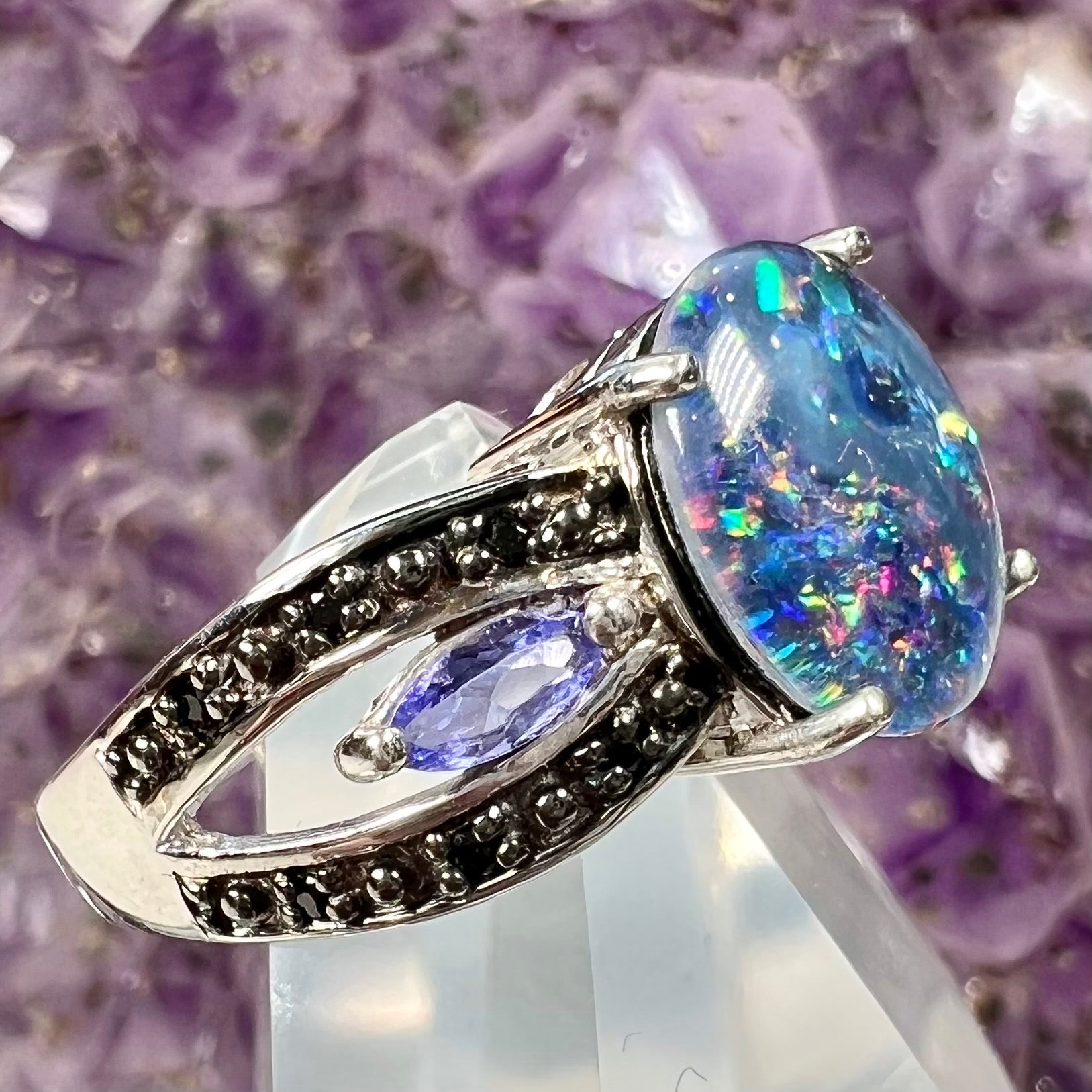 A sterling silver black opal triplet ring set with black spinel and marquise cut tanzanite accent stones.