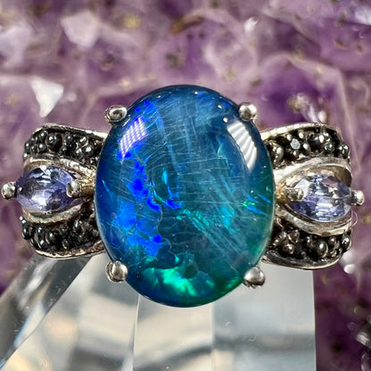 A sterling silver ring set with a black opal triplet, two marquise cut tanzanites, and round black spinel accent stones.