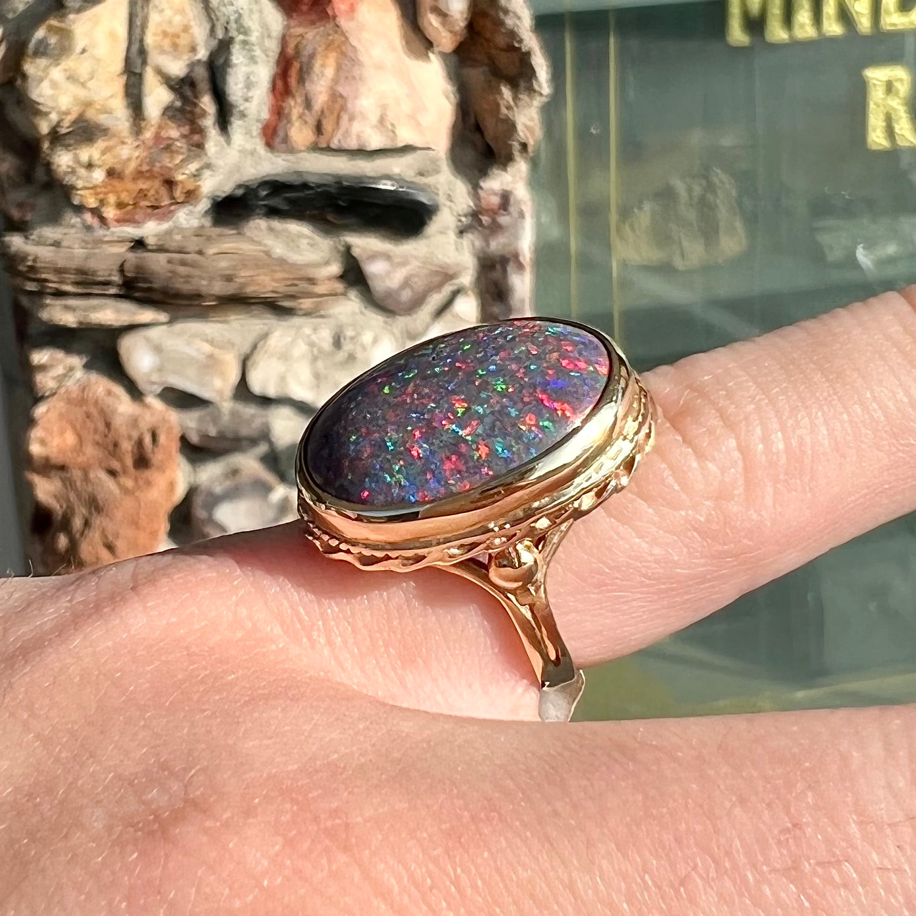 A bright black Andamooka opal that displays a pinfire pattern set in a vintage-style yellow gold bezel ring.