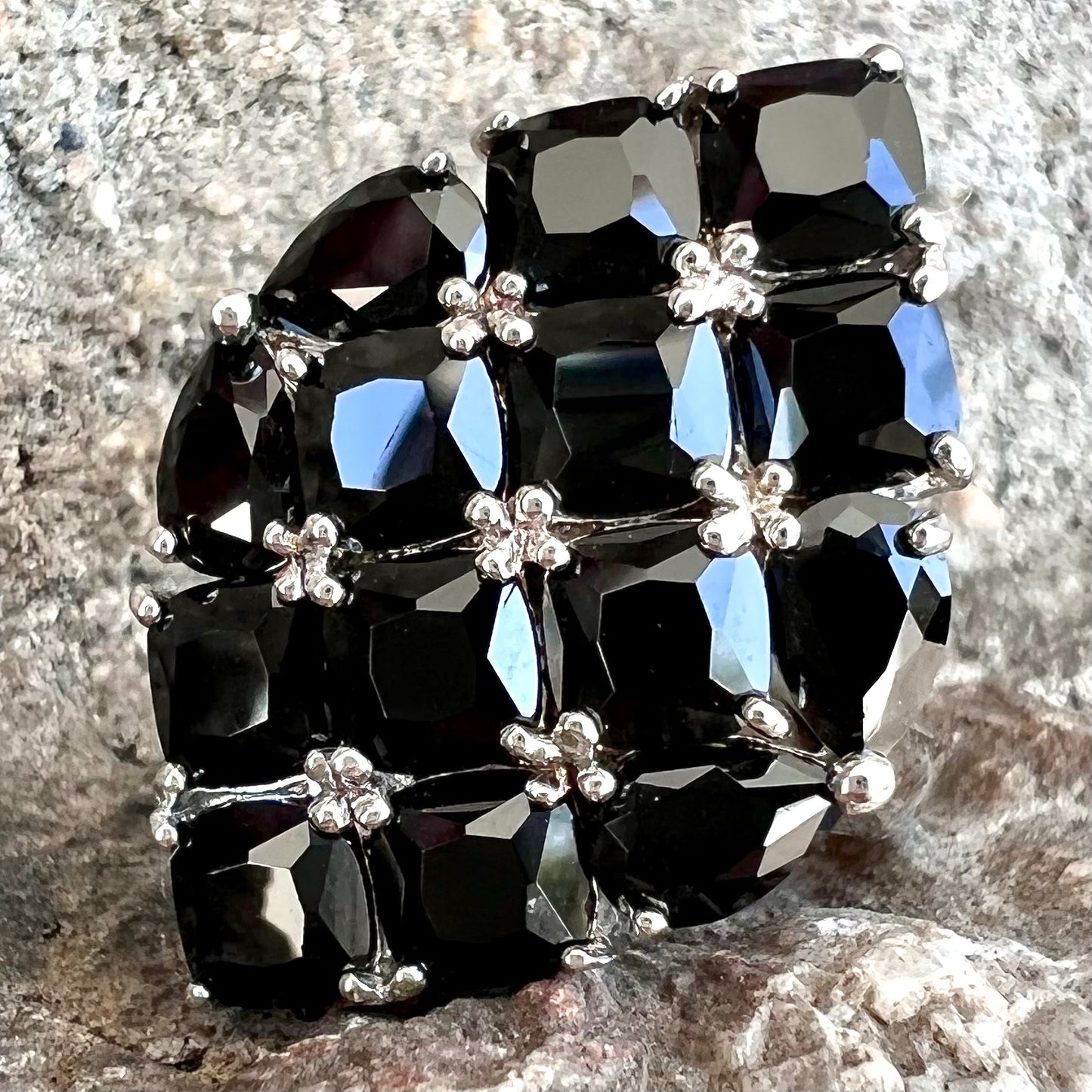 A sterling silver ring cluster set with faceted black spinel stones set to form a marquise shape.