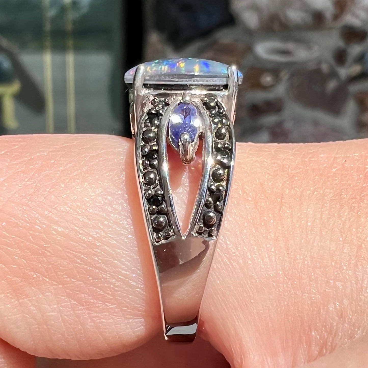 A sterling silver black opal triplet ring set with black spinel and marquise cut tanzanite accent stones.