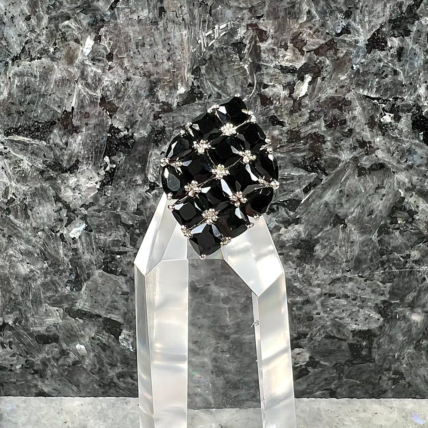 A sterling silver ring cluster set with faceted black spinel stones set to form a marquise shape.