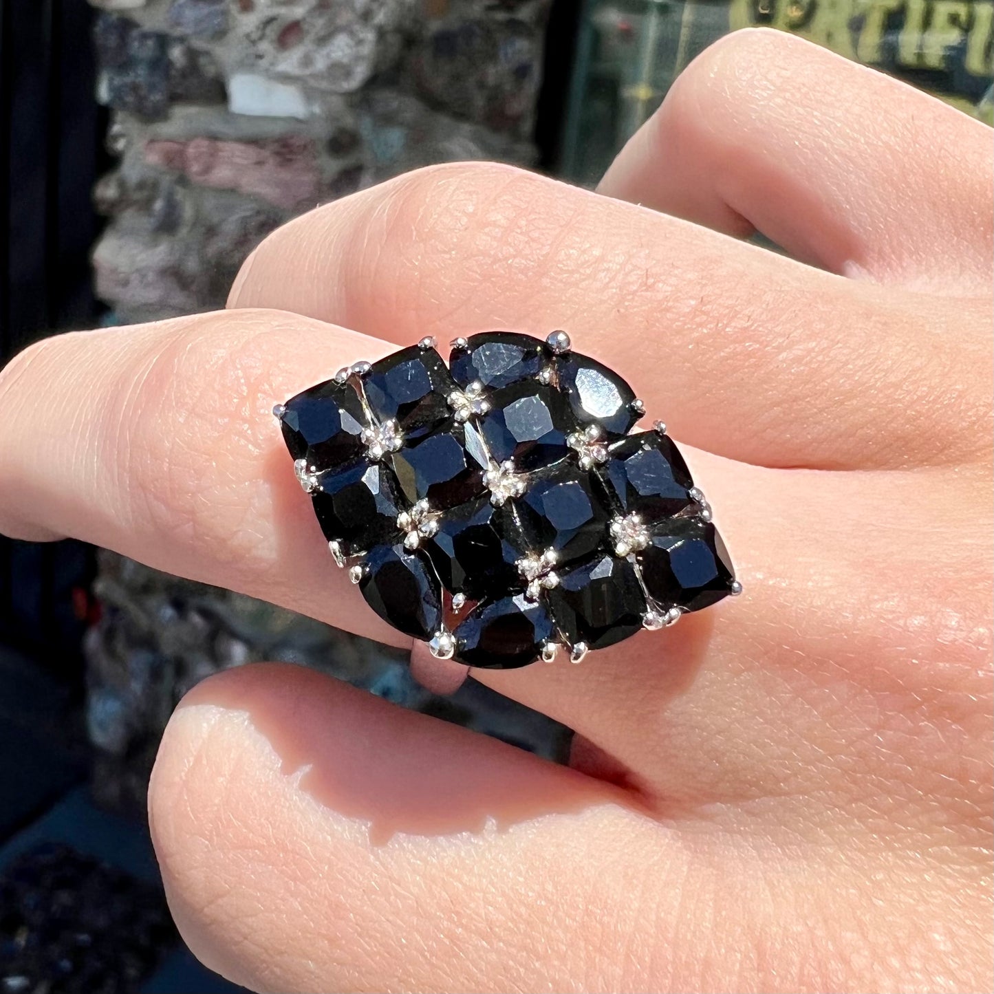 A sterling silver ring cluster set with faceted black spinel stones set to form a marquise shape.