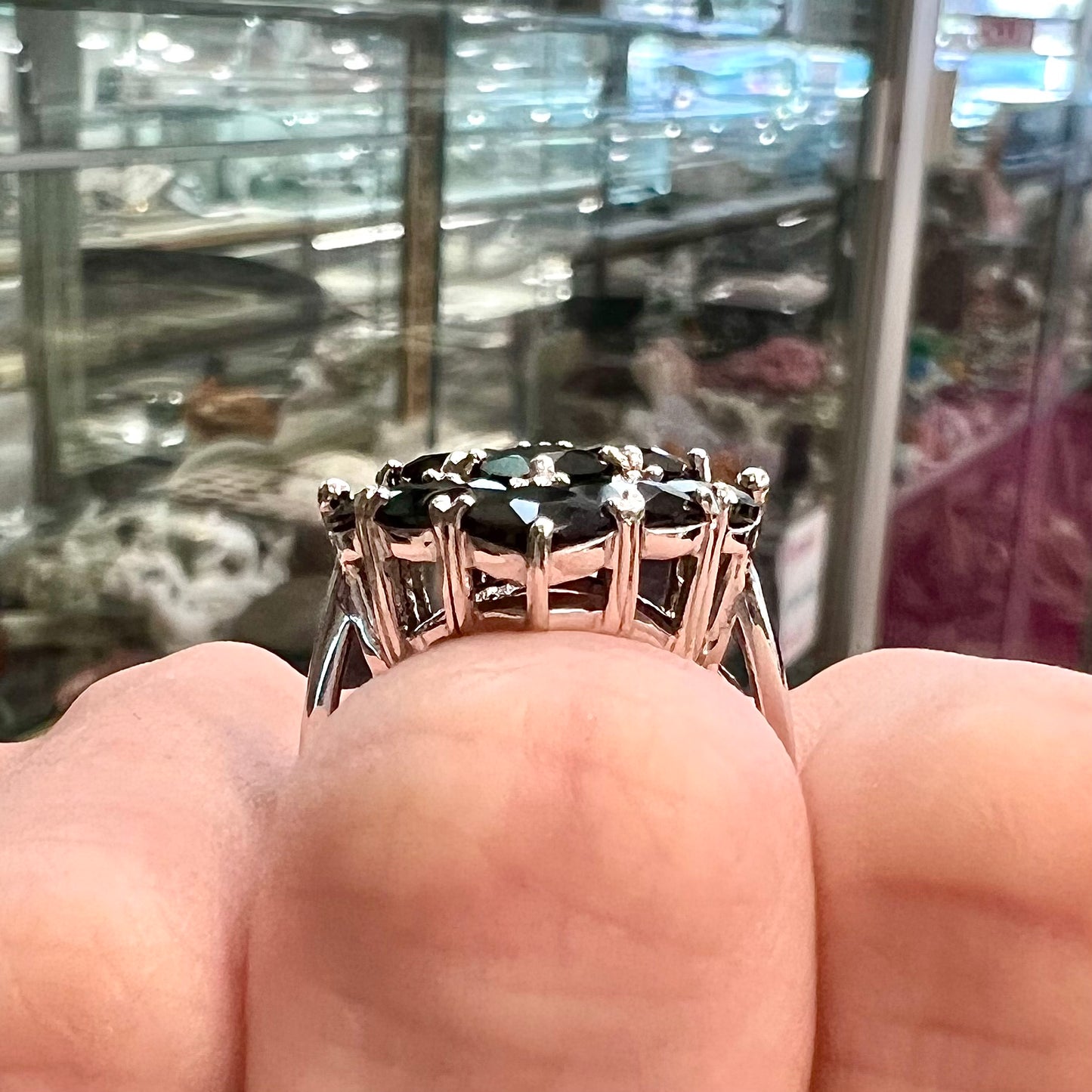 A sterling silver ring cluster set with faceted black spinel stones set to form a marquise shape.