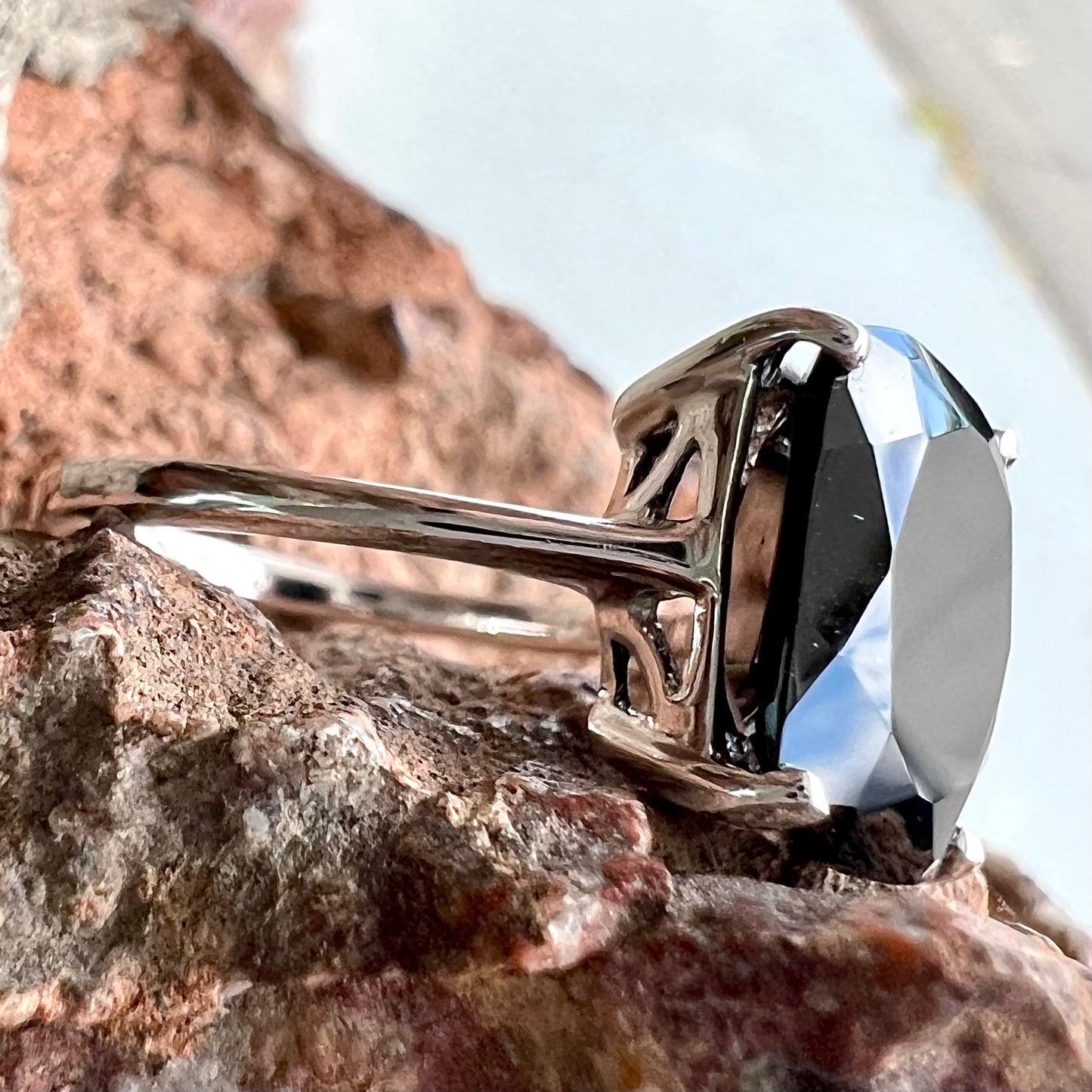 A cushion cut black spinel prong set in a sterling silver solitaire ring.