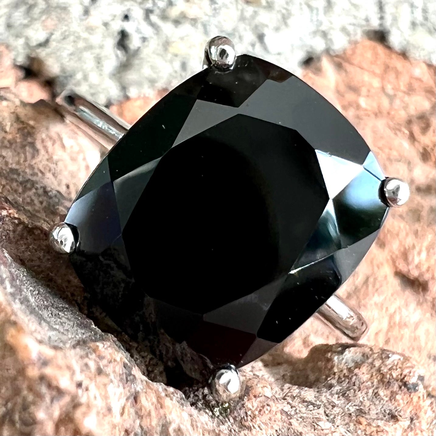 A cushion cut black spinel prong set in a sterling silver solitaire ring.