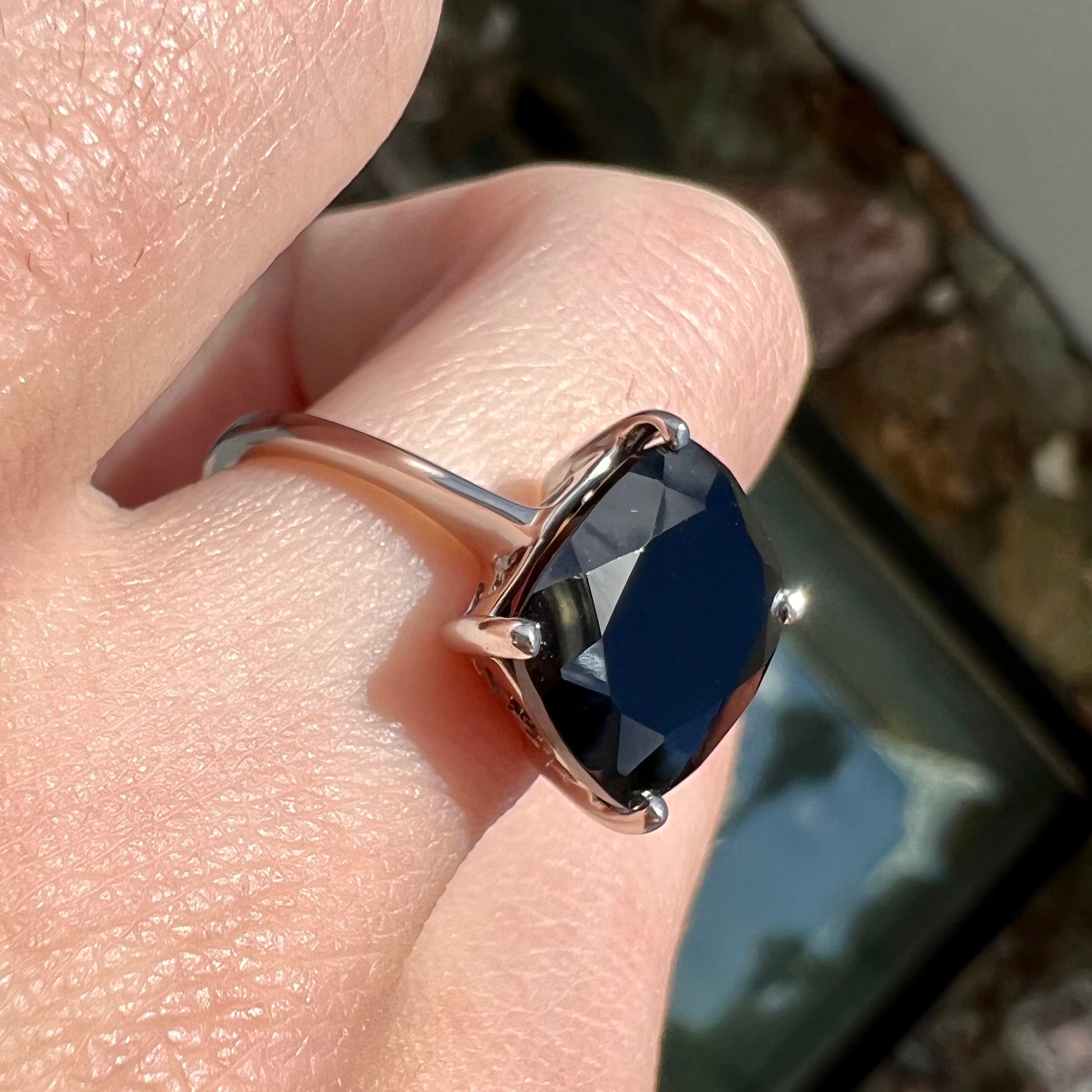 A cushion cut black spinel prong set in a sterling silver solitaire ring.