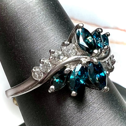A white gold diamond cluster ring set with blue marquise cut and white round cut diamonds.