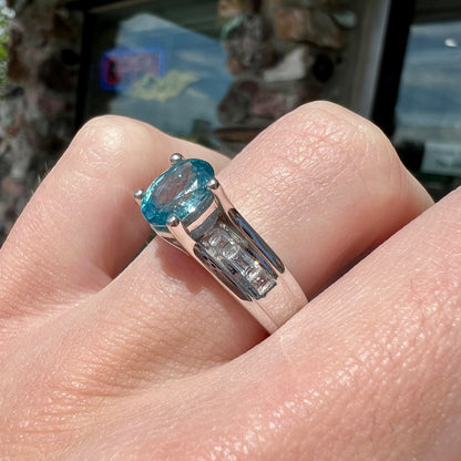 A sterling silver ring set with an oval cut blue zircon center stone and channel set white zircon accents.