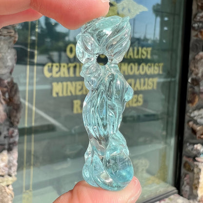 A stone woman figure carved from a blue aquamarine crystal.  The piece resembles Venus Gummi de Milo.