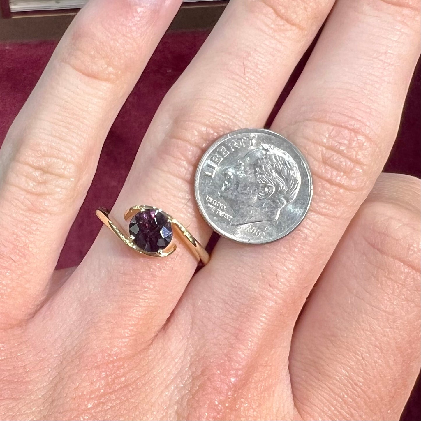 A yellow gold solitaire engagement ring set with a faceted oval cut color change garnet stone.