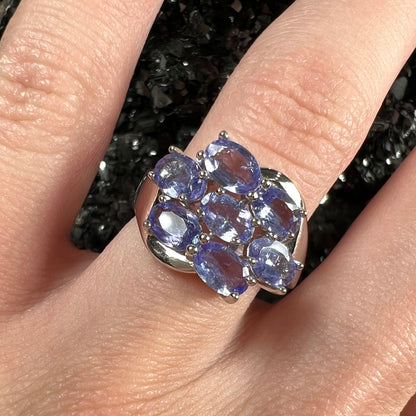 A sterling silver cluster ring prong set with seven faceted oval cut blue tanzanite stones.