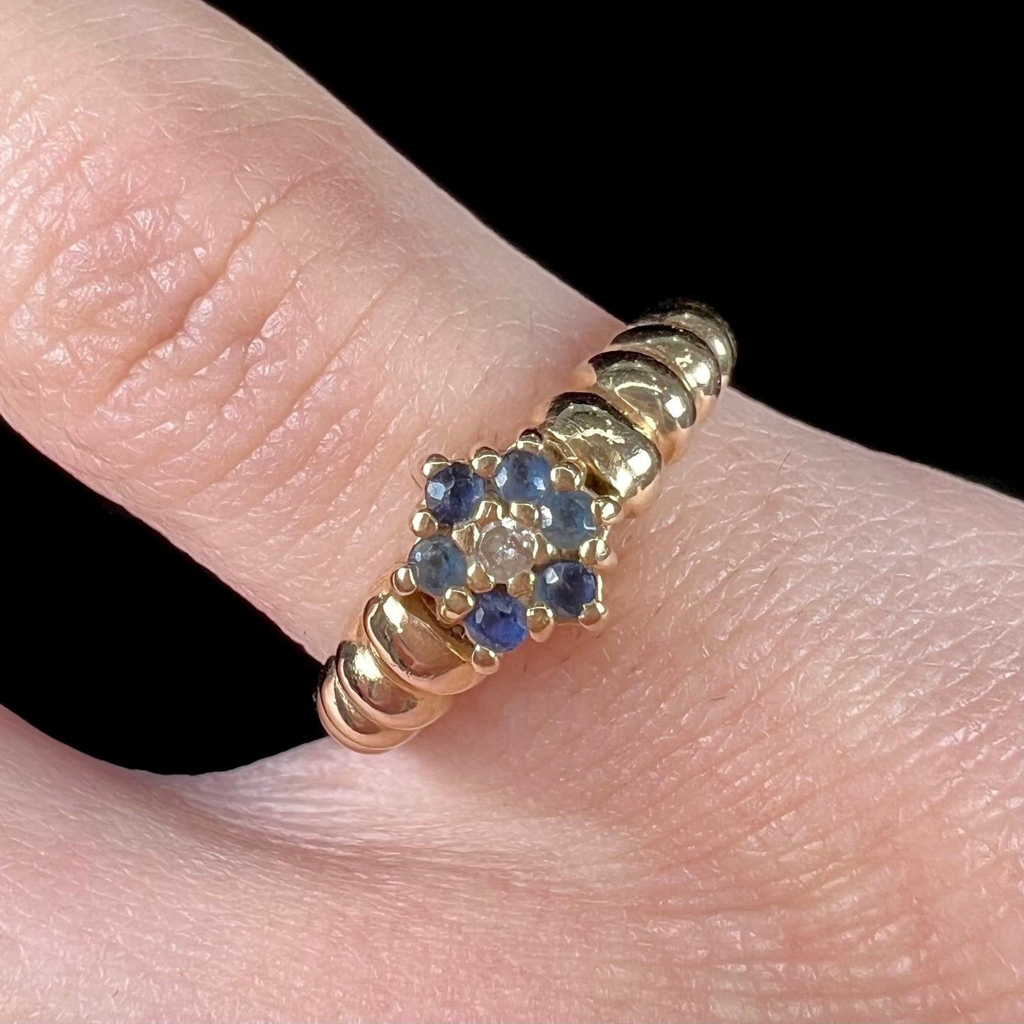 A ladies' yellow gold cluster ring set with round blue sapphires and a round diamond.