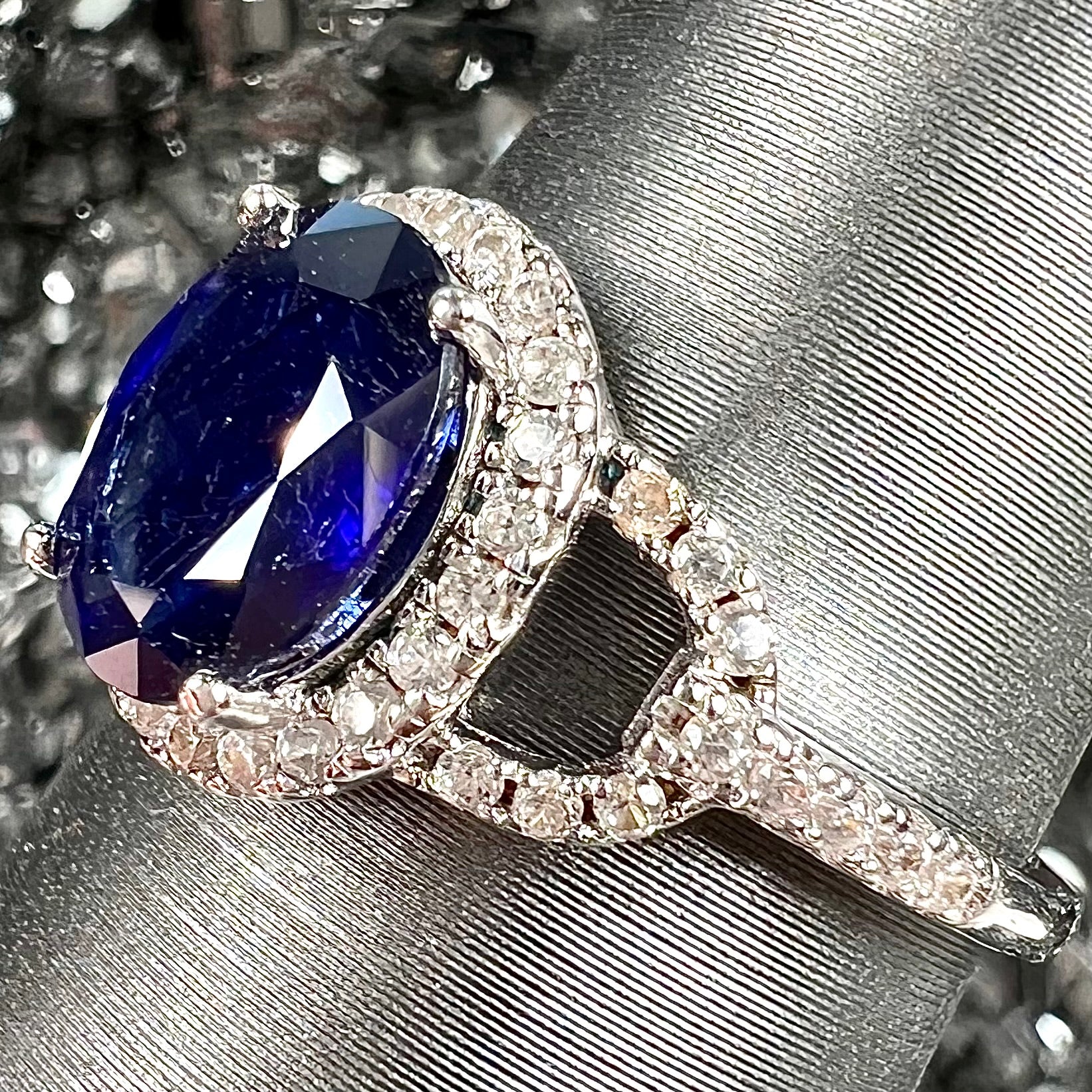 A sterling silver, white zircon halo ring set with an oval cut blue sapphire.