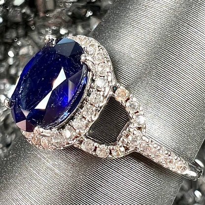 A sterling silver, white zircon halo ring set with an oval cut blue sapphire.