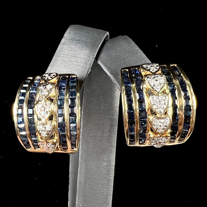 A pair of gold omega back earrings channel set with blue sapphires and heards set with diamonds.
