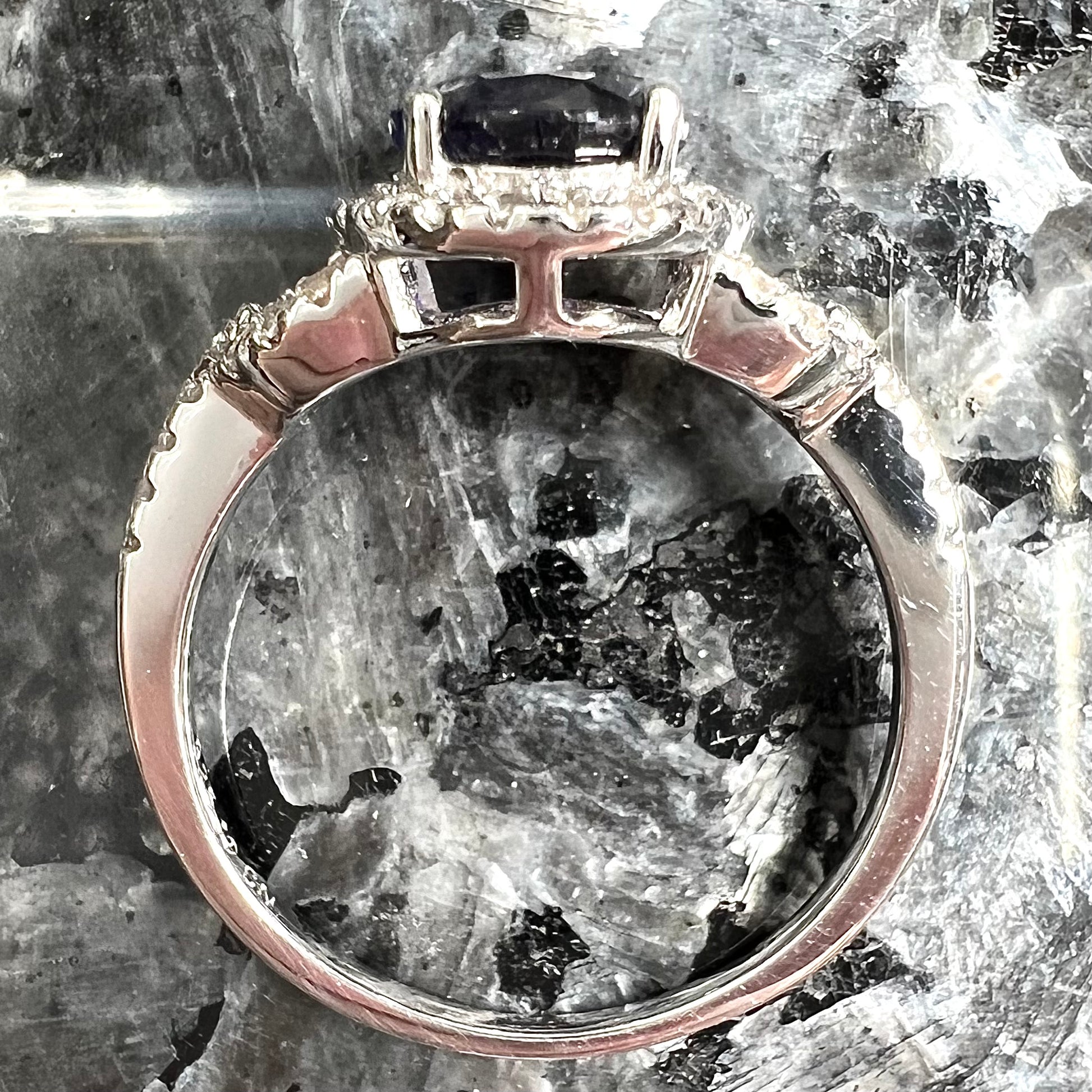 A sterling silver, white zircon halo ring set with an oval cut blue sapphire.