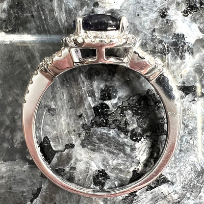 A sterling silver, white zircon halo ring set with an oval cut blue sapphire.
