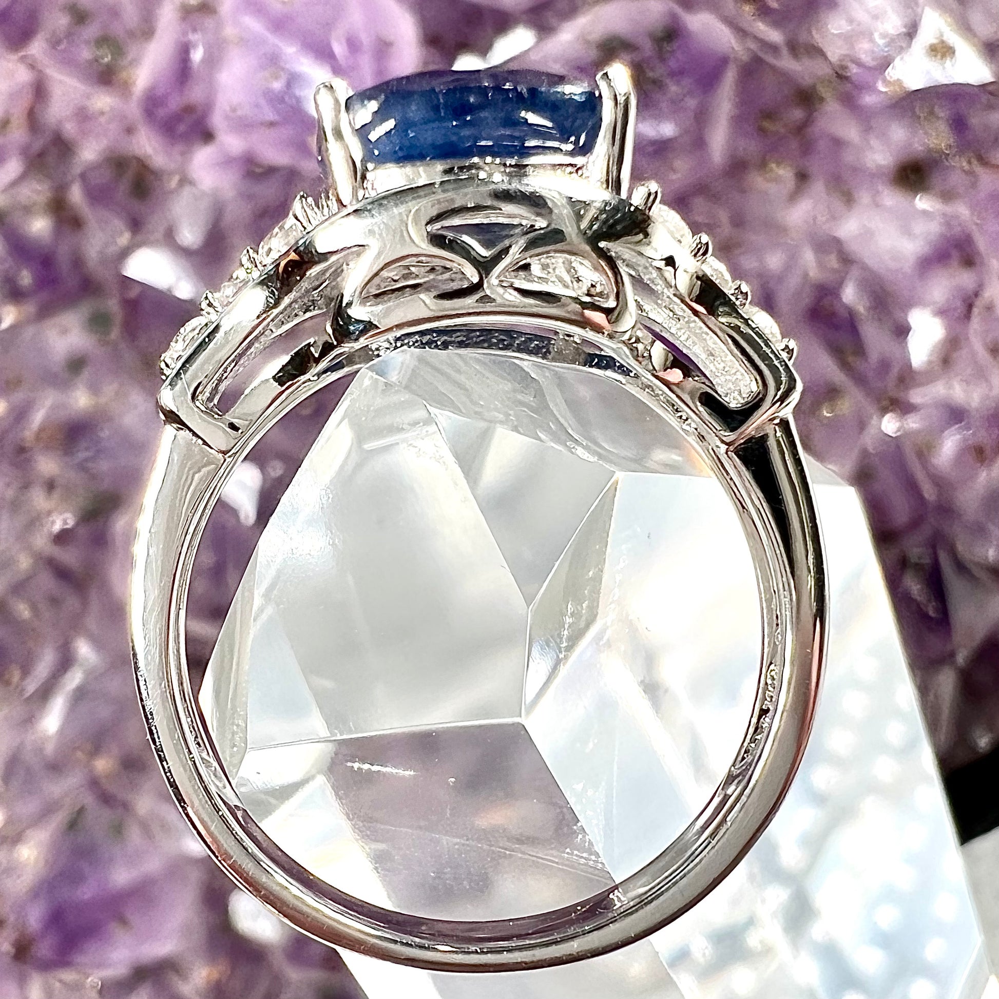 A sterling silver ring set with a cushion cut blue sapphire center stone and round cut white sapphire accents.