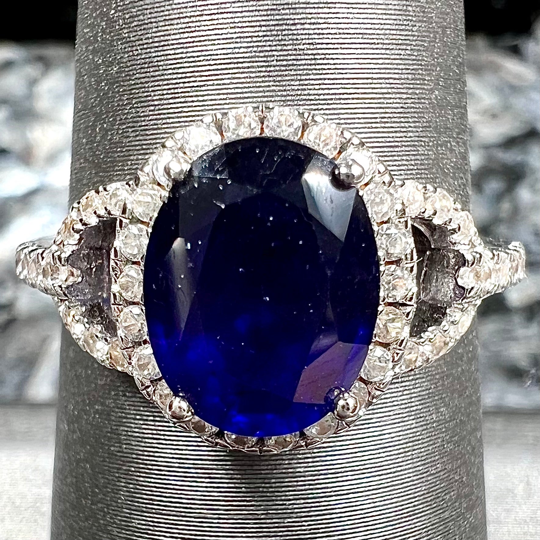 A sterling silver, white zircon halo ring set with an oval cut blue sapphire.