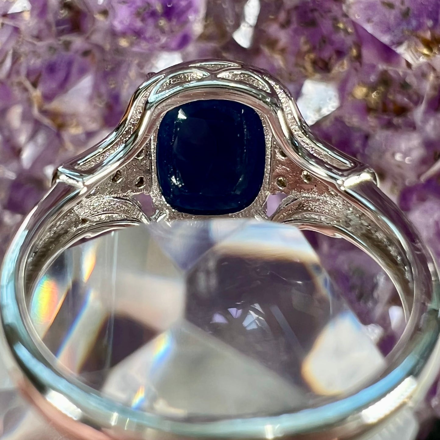 A sterling silver ring set with a cushion cut blue sapphire center stone and round cut white sapphire accents.