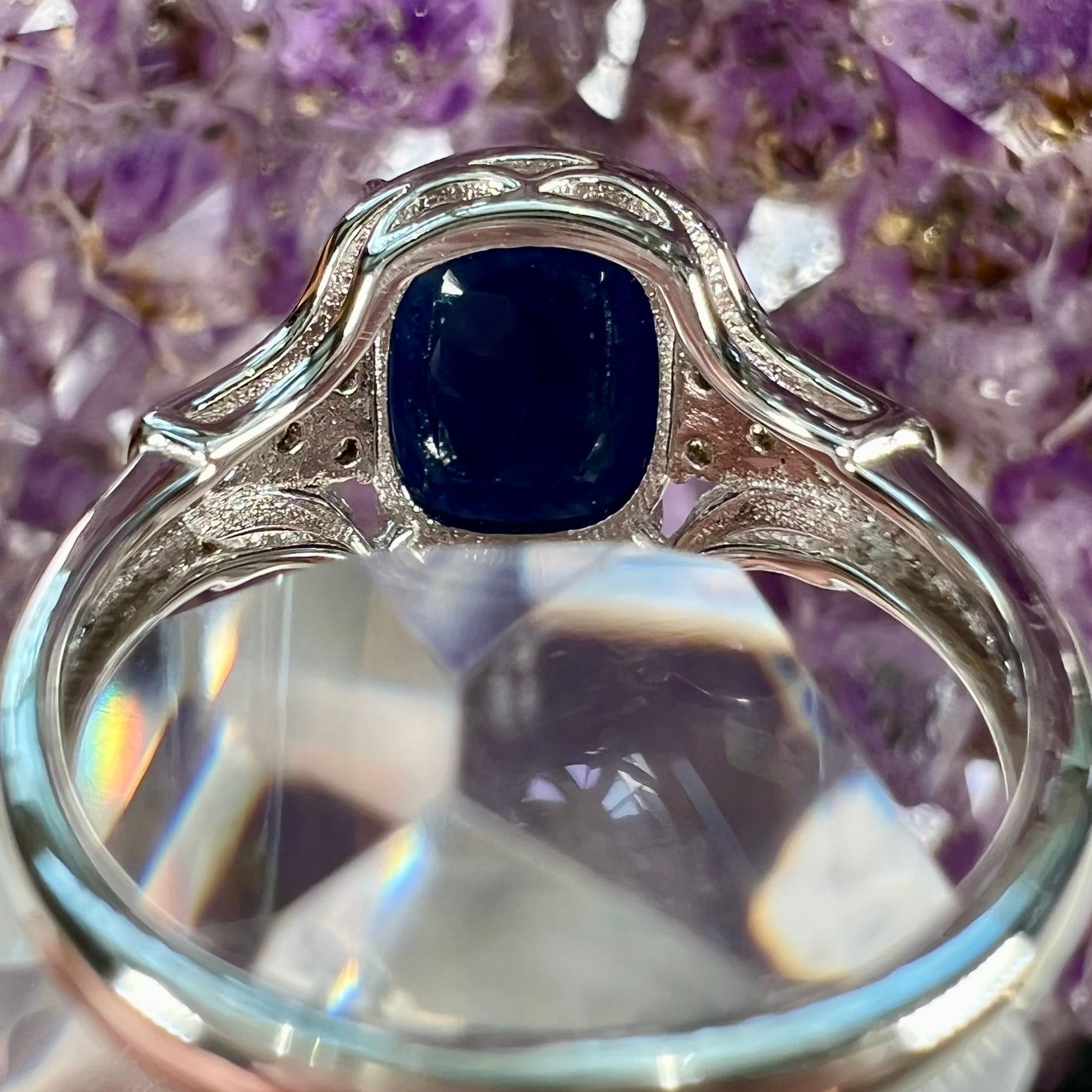 A sterling silver ring set with a cushion cut blue sapphire center stone and round cut white sapphire accents.