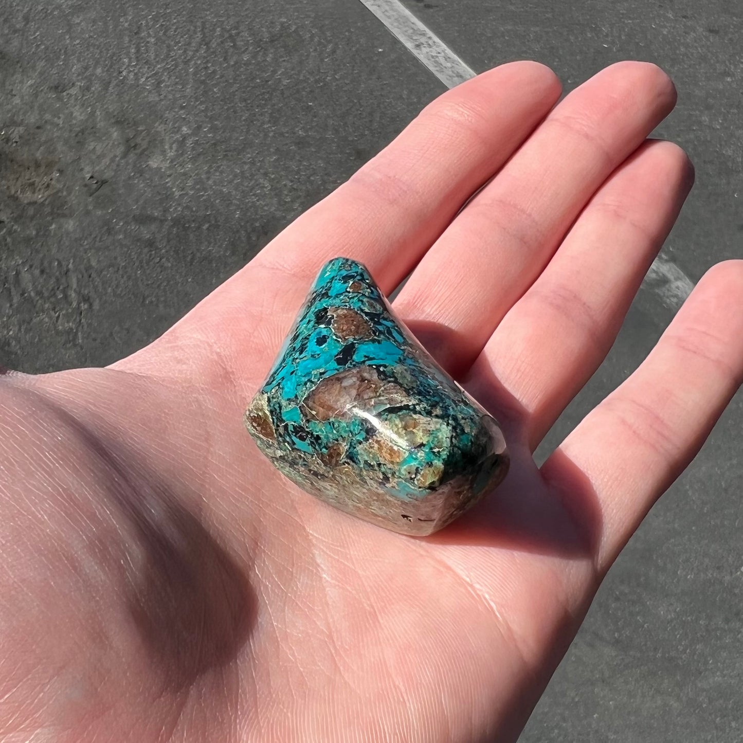 A loose polished chrysocolla stone with malachite inclusions.