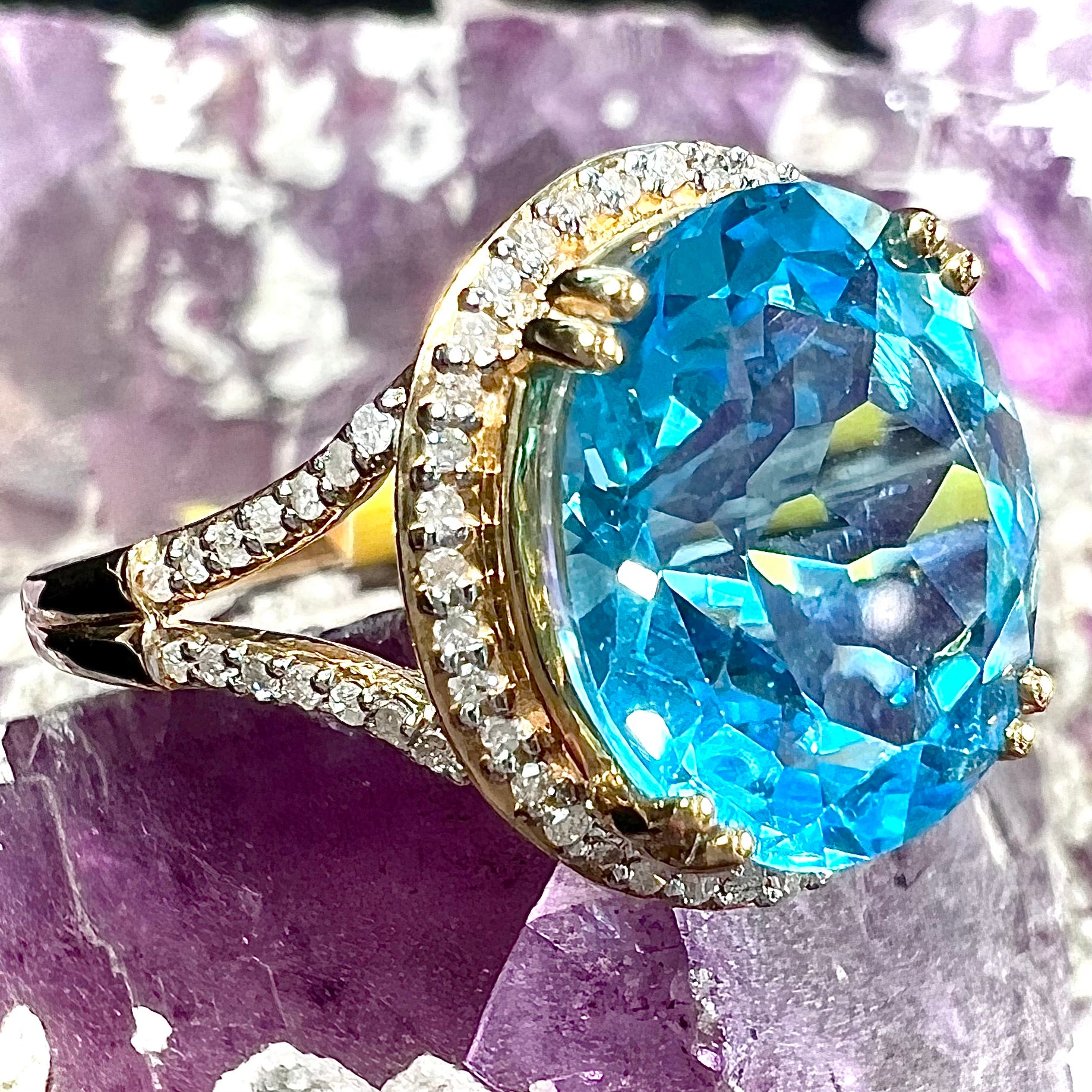 An oval cut Swiss blue topaz and diamond pave split shank ring in yellow gold.