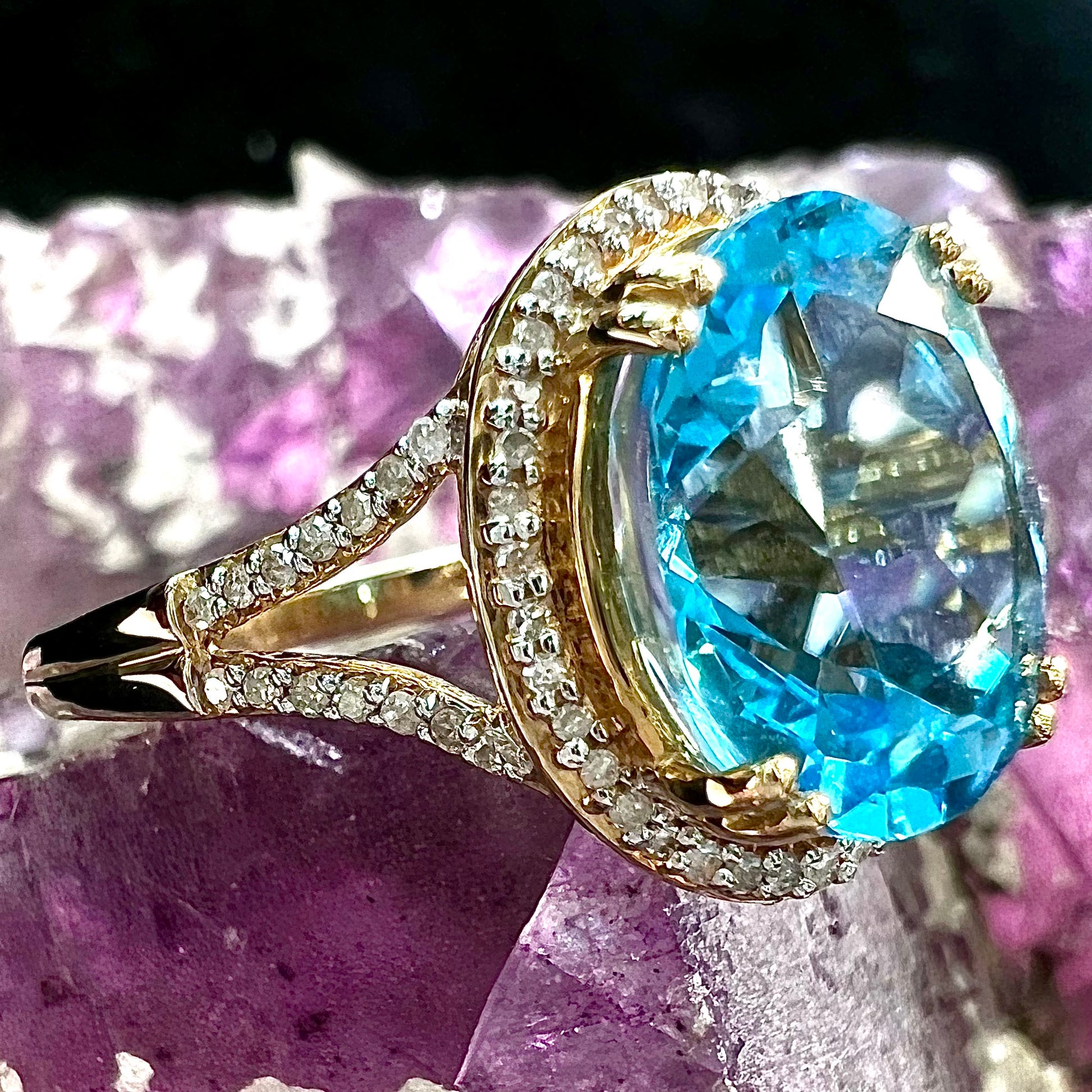 An oval cut Swiss blue topaz and diamond pave split shank ring in yellow gold.