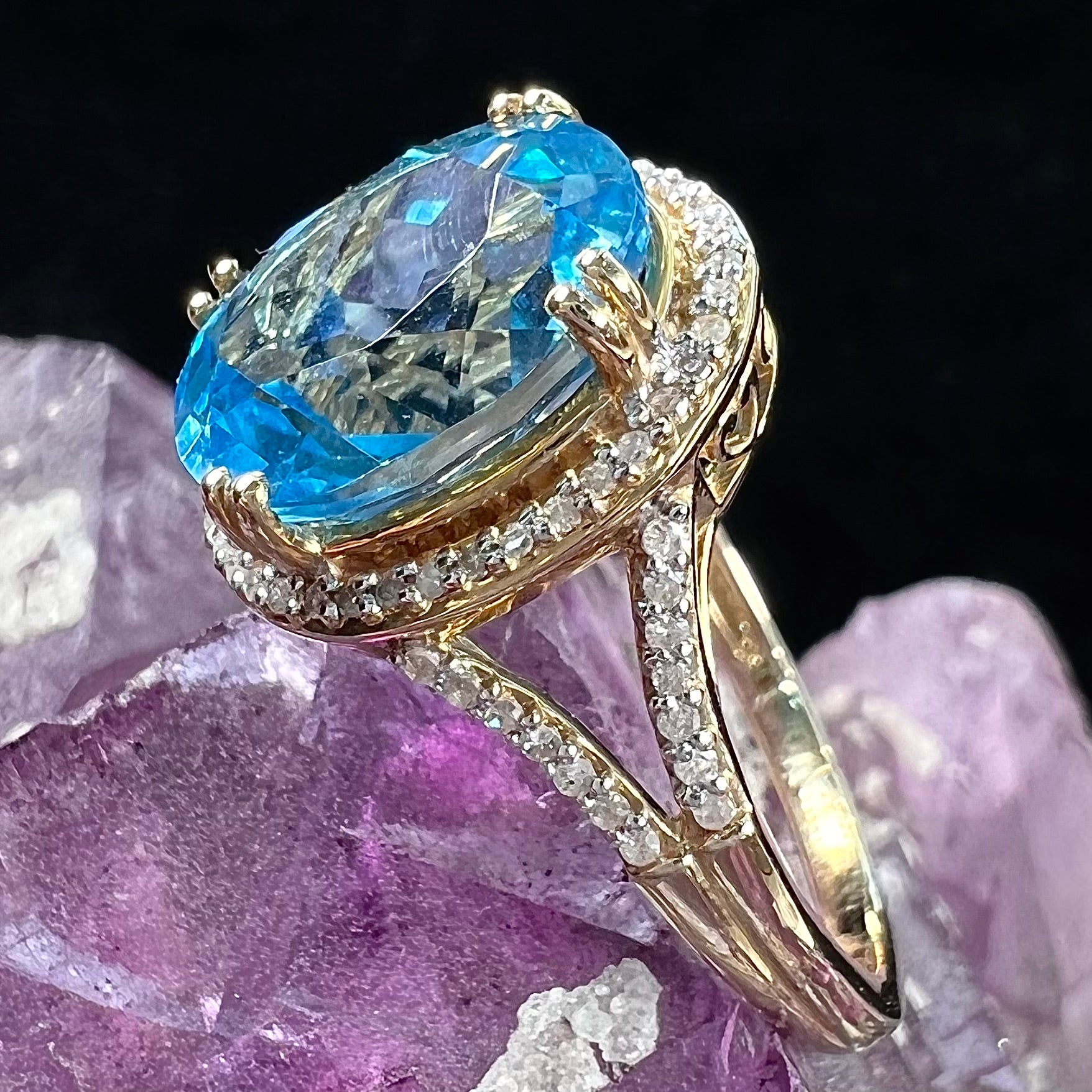 An oval cut Swiss blue topaz and diamond pave split shank ring in yellow gold.
